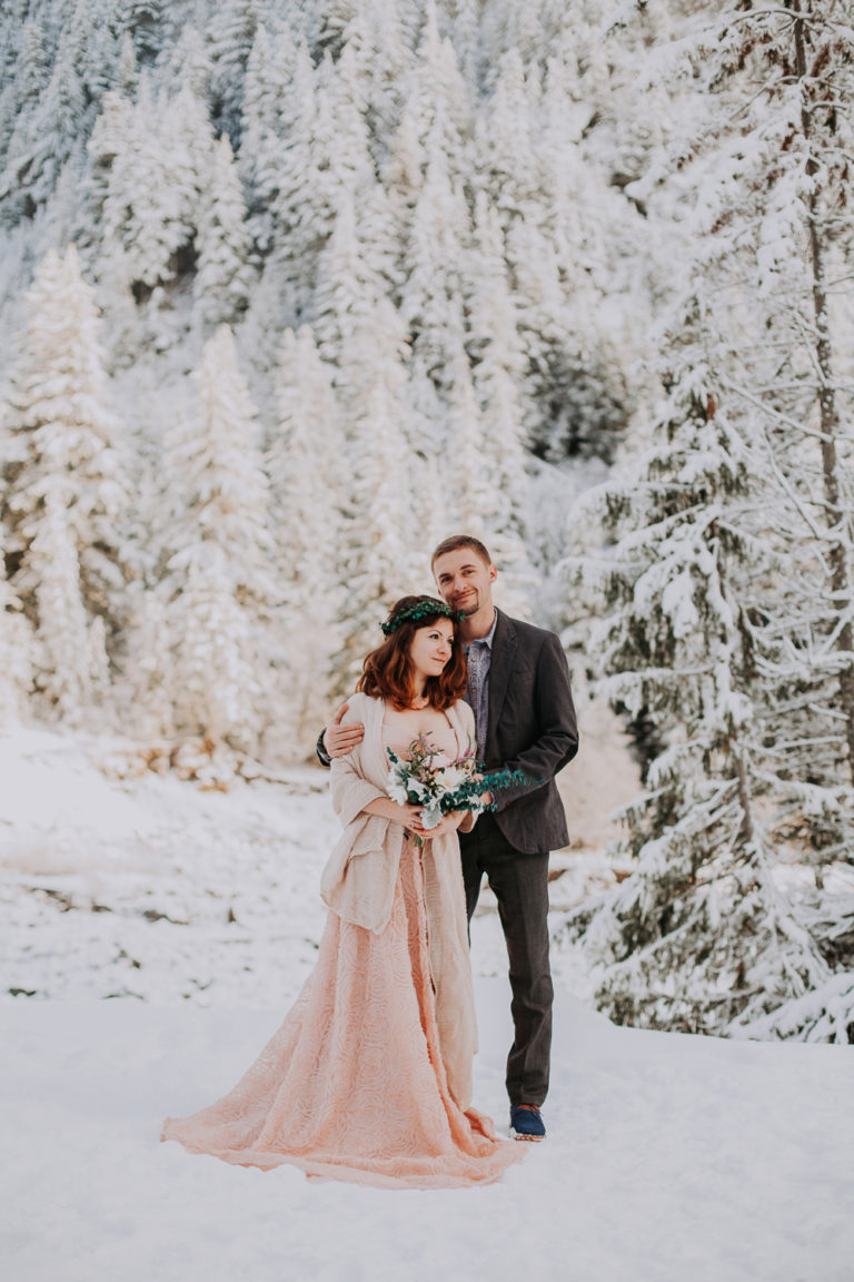 Elopement at Mount Rainier in winter at sunset time. Golden hours and snow in Rocky Mountains. Blush pink wedding dress in snow