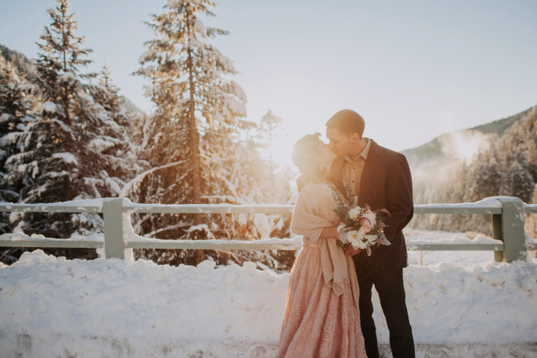Elopement at Mount Rainier in winter at sunset time. Golden hours and snow in Rocky Mountains. Blush pink wedding dress in snow
