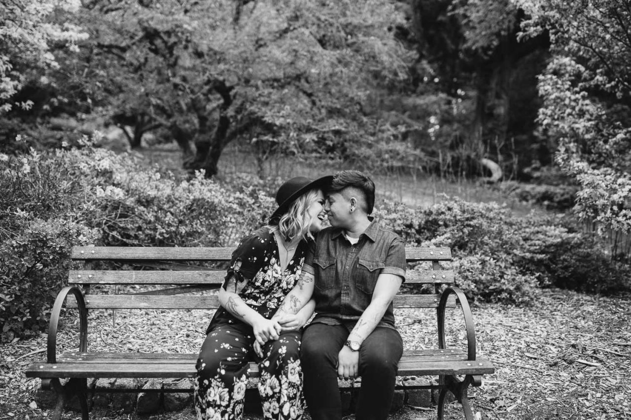 Beautiful same sex couple in spring engagement session with cherry blossom in Seattle Arboretum